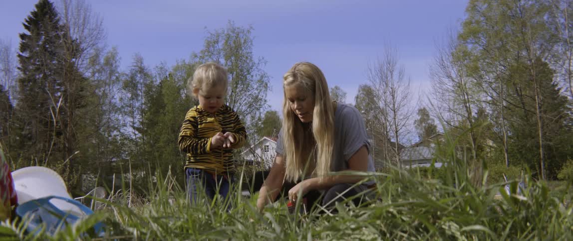 Young boy and woman engaging in outdoor planting activities in a beautiful meadow.