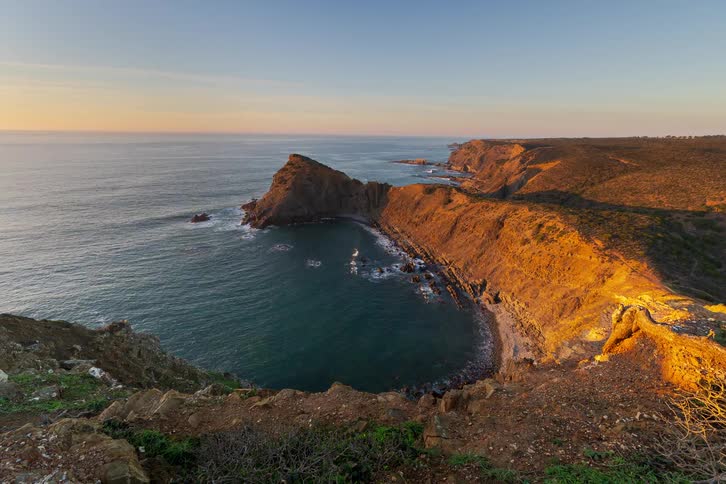 Ocean waves roll into the shore near coastal cliffs and promontories