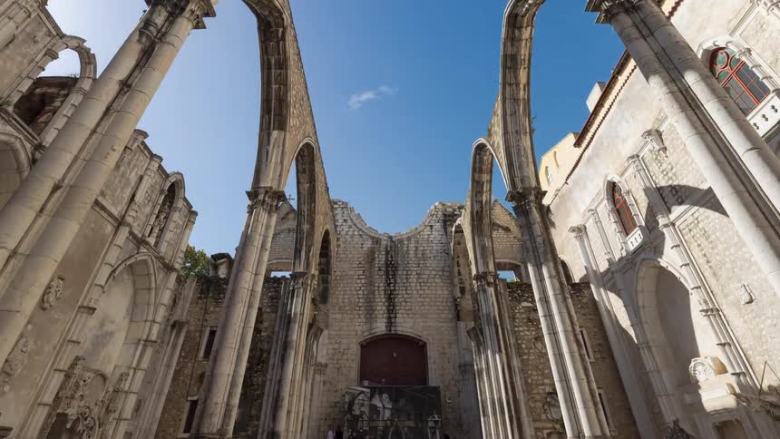 Ruins of a historic building with people passing walking by next to it