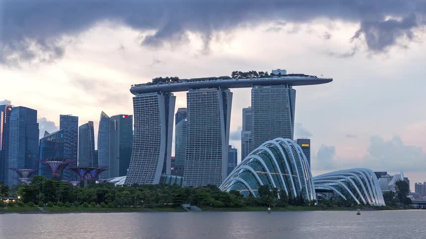 Clouds pass over city buildings with creative architecture as night falls