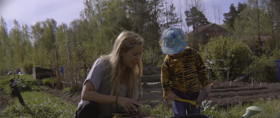 Woman talking with a child while they work in a field on a cloudy day