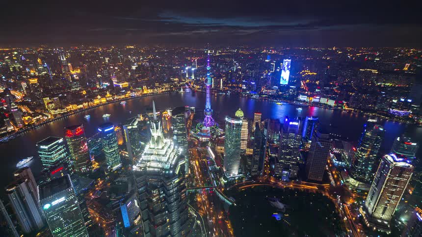 Illuminated skyscrapers at night around a river with an observation tower highlighted in the center of the city
