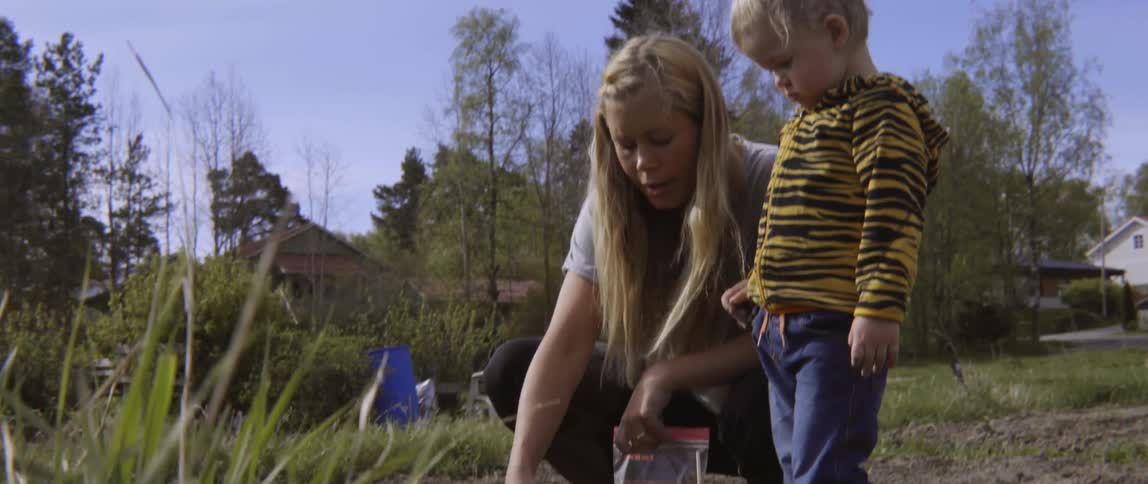 A woman talks to a child as she digs a hole in a garden