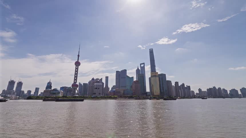 A wide shot captures the shanghai skyline across the huangpu river under a clear sky