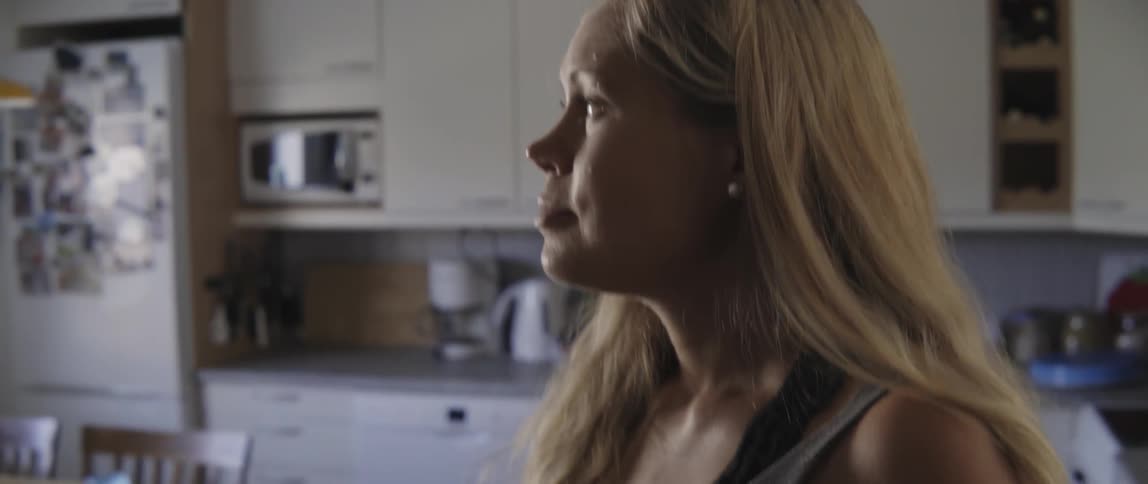 Pregnant woman standing in her kitchen and feeling her bulging belly