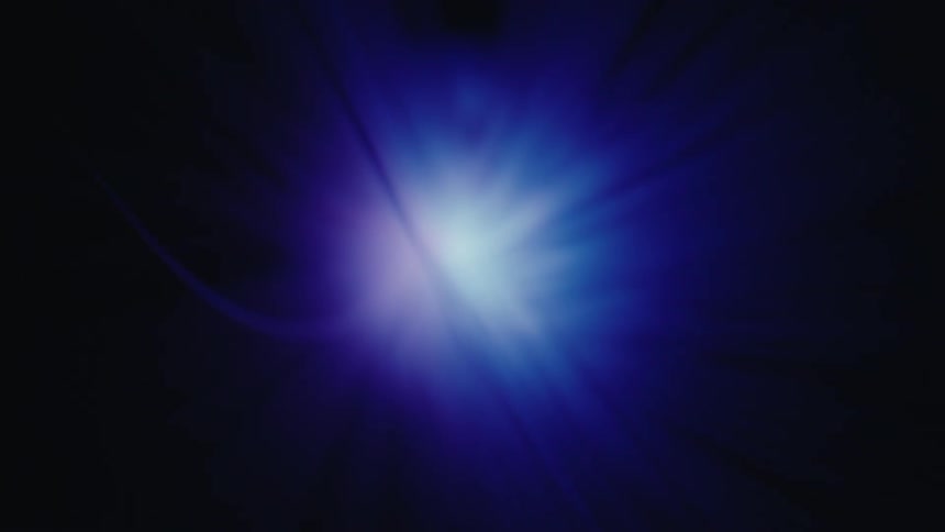 A bright white light bursts from the center of a dark blue void casting long radial beams and a soft cyan glow across the frame in an abstract display of energy and motion