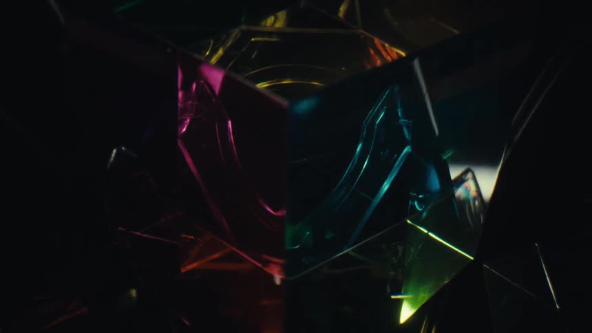 Translucent geometric surfaces reflecting colorful lights in a dark environment
