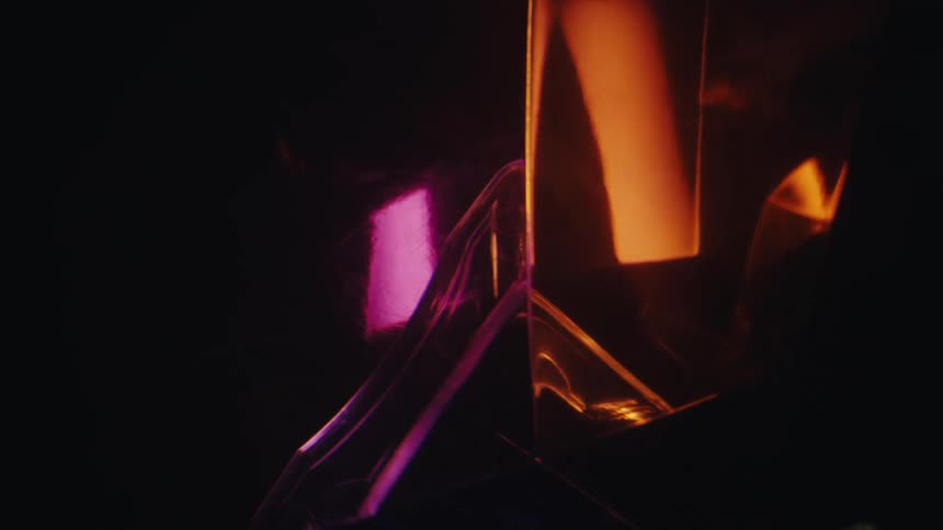 A geometric glass structure refracting blinking lights of different colors in a dark room