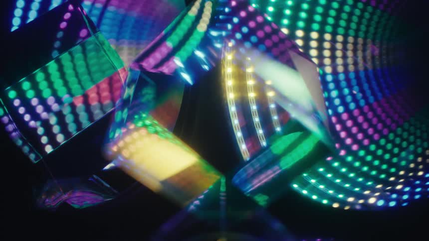 A close view shows glass prisms reflecting vibrant patterns of blue and green light dots against a dark background while yellow light beams pass through the facets