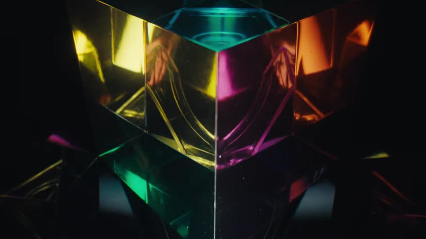 Geometric prismatic glass structure reflecting colored lights in a dark environment