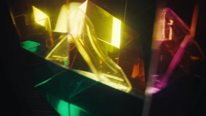Colored light reflections passing through geometric glass structures and prismatic surfaces