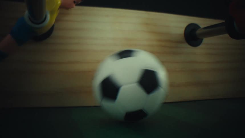 Plastic men in a foosball table move and hit the ball