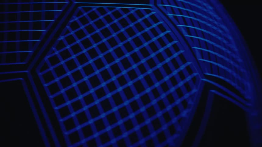 Part of a soccer ball illuminated in blue with a hexagon pattern against a dark background