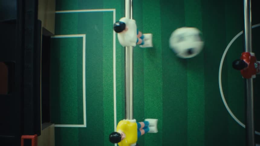 Foosball player figure attached to a metal rod over a green field with soccer markings