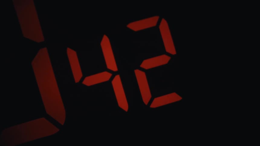 Digital clock display showing red numbers counting up indoors