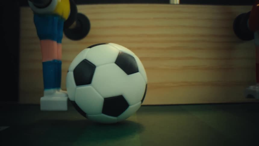 Soccer ball on a foosball table with figurines attached to metal rods