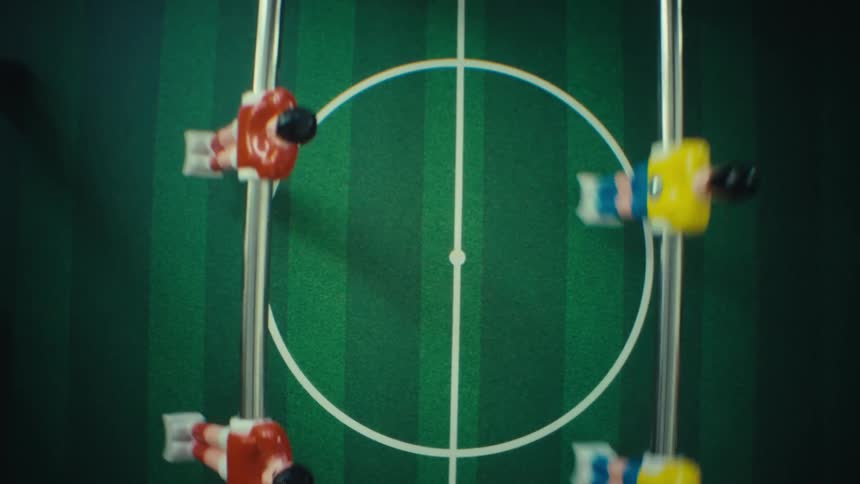 Foosball player figures on metal rods near a ball on a marked green field