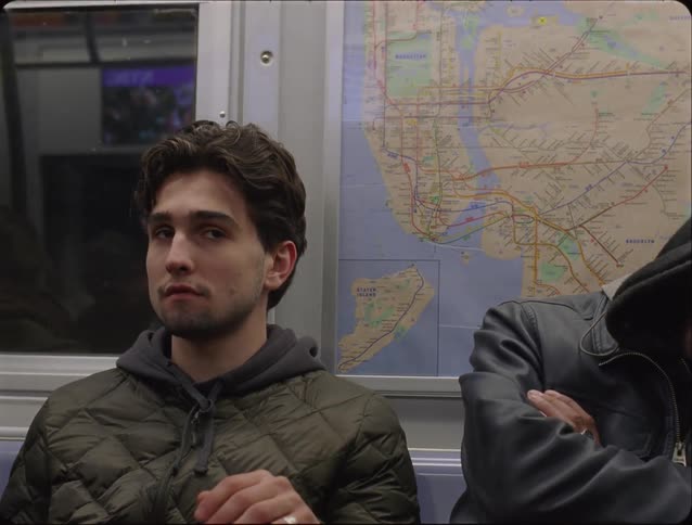 A young man sitting inside a metro train during a ride next to another person at night