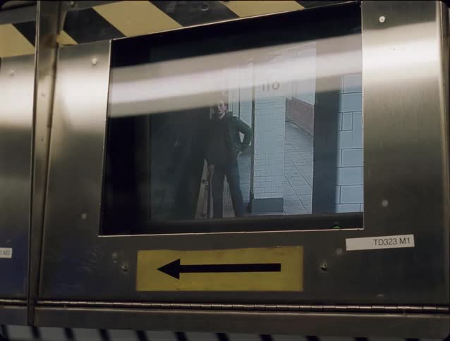 Screen in a subway station shows a man walking with a skateboard