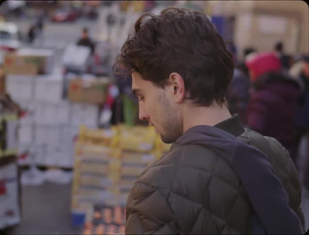 Young man walking around looking at fruit at an outdoor farmers market