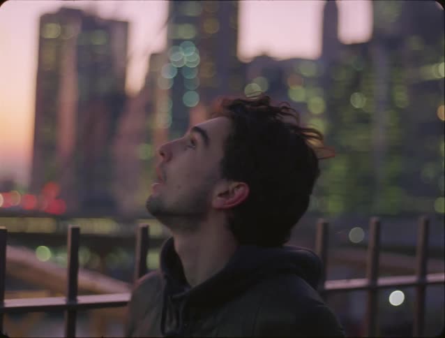 Man walking across a bridge in a metropolis and observing his surroundings