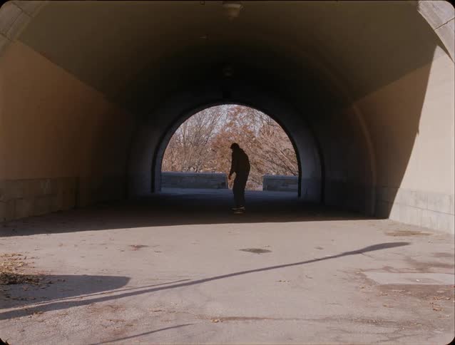 A person skateboarding into a tunnel