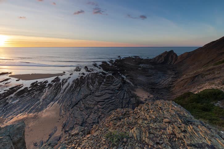 Time lapse of the sun setting over a rocky coastal landscape
