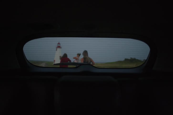 Three women enjoying a seaside vacation on a coastal path with a lighthouse in the background