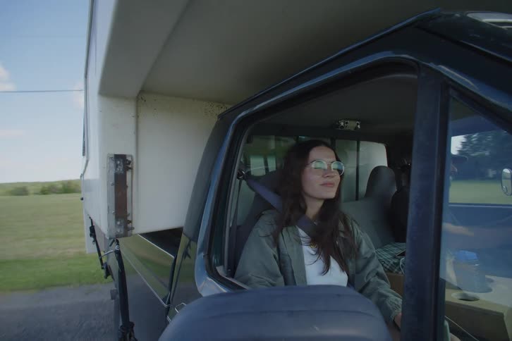 Woman wearing glasses sitting in the passenger seat of a vehicle driving on farmroads