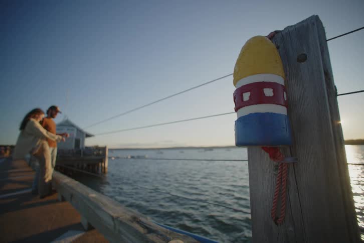 A man and woman standing on a pier near the ocean