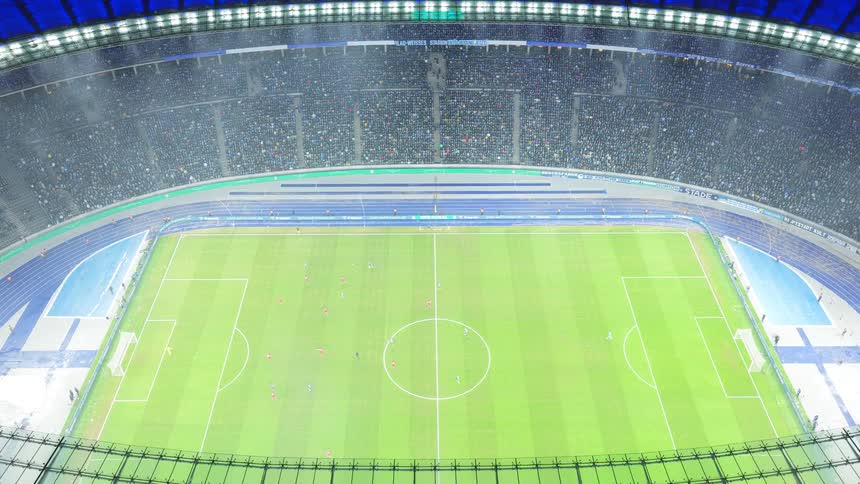 A soccer game played in a large stadium with a crowd of spectators