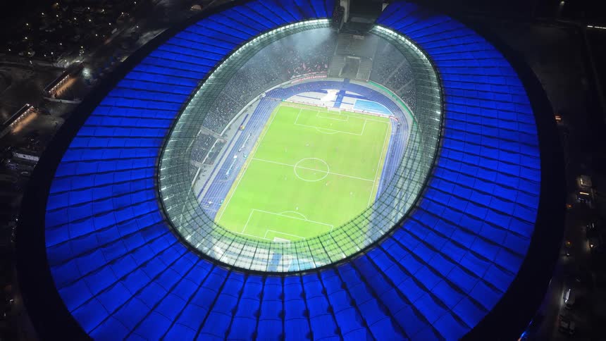 Aerial view of a soccer stadium with players on the field and people in the stands