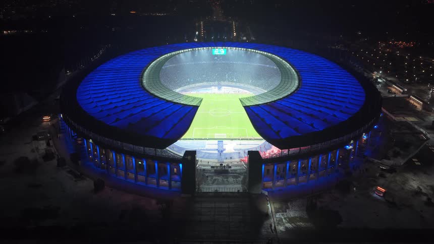 Circular stadium illuminated at night with a soccer field visible in the center
