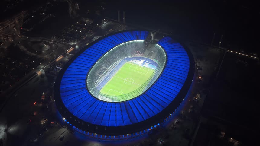 Oval stadium illuminated at night with a soccer field visible in the center