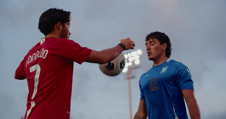 Soccer players play one on one soccer on a soccer field in the evening
