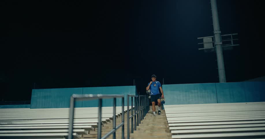 A man walking down the stadium stairs at night