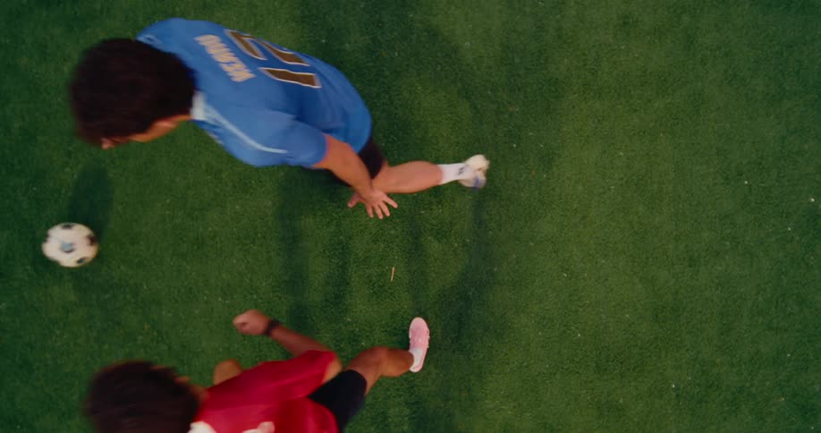 A topdown shot shows a referee or player dropping a soccer ball between two opponents on a green turf fieldas the ball hits the ground both players immediately sprint in opposite directions toward their respective sides