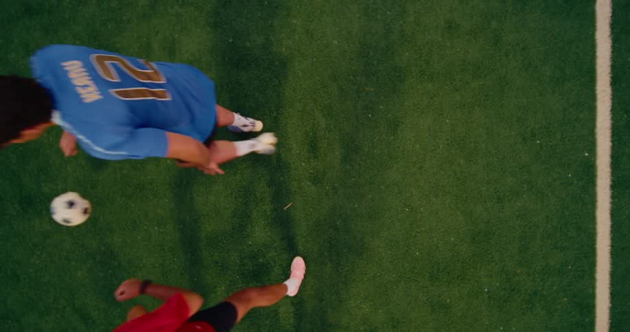 Two young adult male soccer players waiting for a drop ball and then kicking and dribbling away on a soccer field outdoors during day time