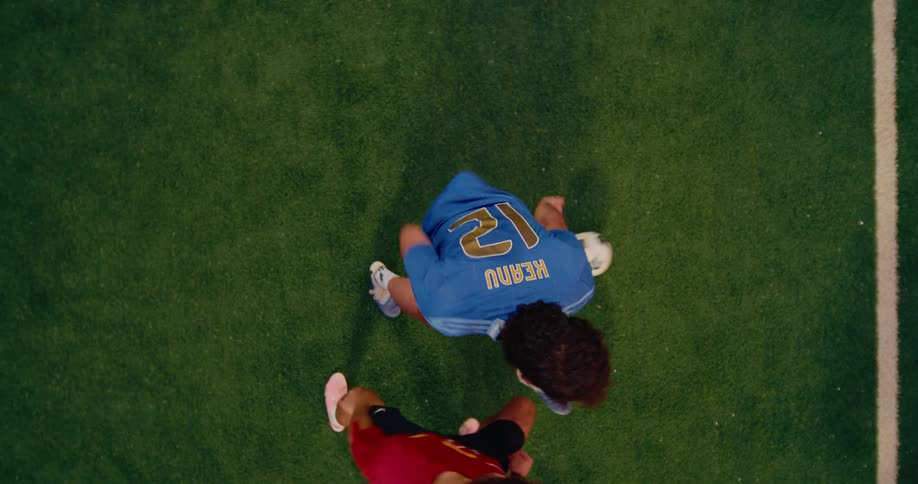 Player wearing blue number 12 jersey contesting the ball with another player on a soccer field seen from above