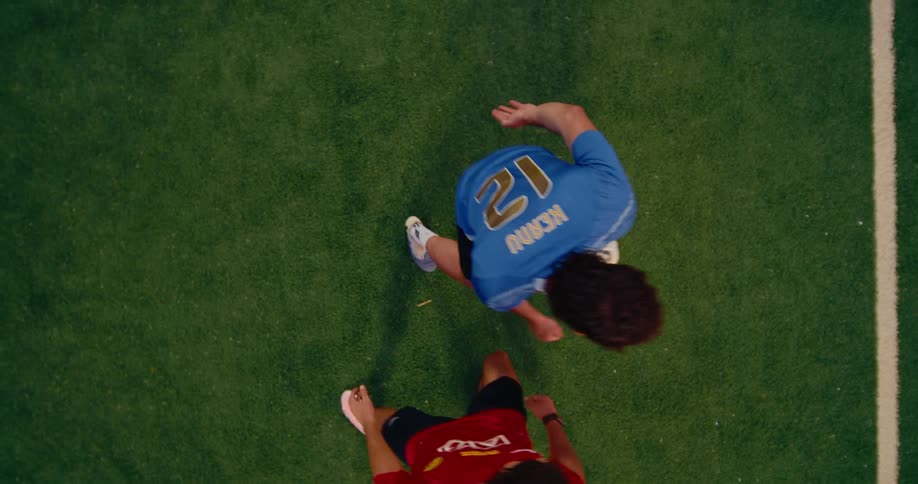 From a birdseye view a soccer player in a blue argentina jersey tosses a ball into the airhe then quickly heads the ball toward his teammate and runs off the green turf