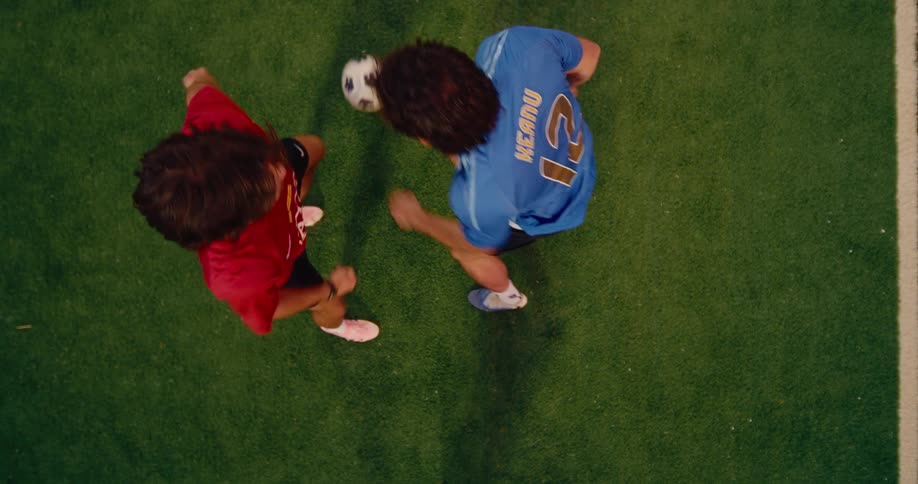 Two soccer players face each other as the ball is tossed into the air and kicked away as they play