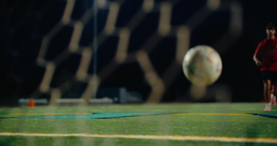 Soccer player moves on the field kicking the ball into the goal