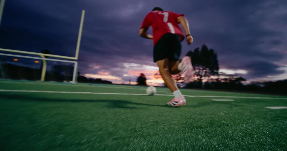 Soccer player moves the ball down the field and kicks toward the goal