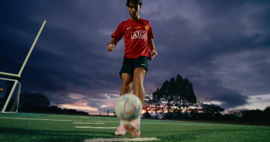 A man juggling ball on the soccer field at night