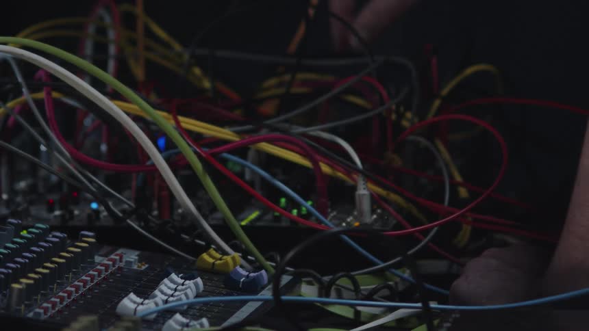A man attaches cords to an electronic soundboard