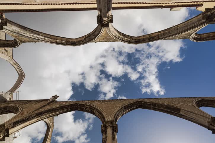 View looking up from an arched building structure as clouds move across the sky