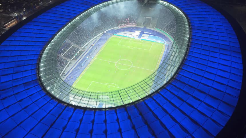 Aerial view of a soccer stadium with players on the field and people in the stands
