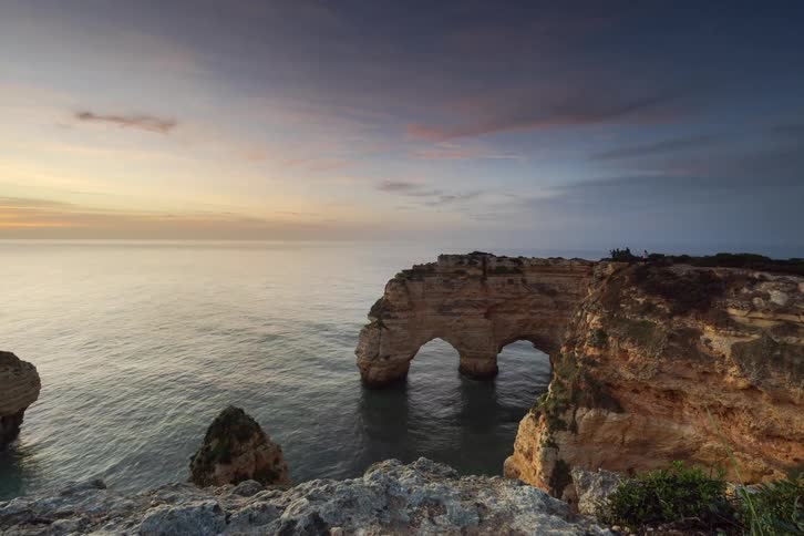 Time lapse video of a natural rock arch on a coastline at sunrise