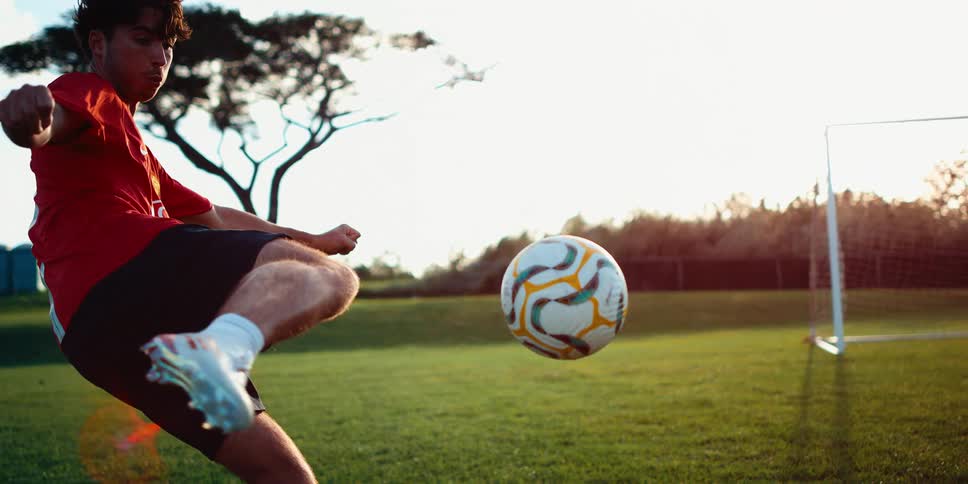 A football player kicking a soccer ball across the field toward the goalpost