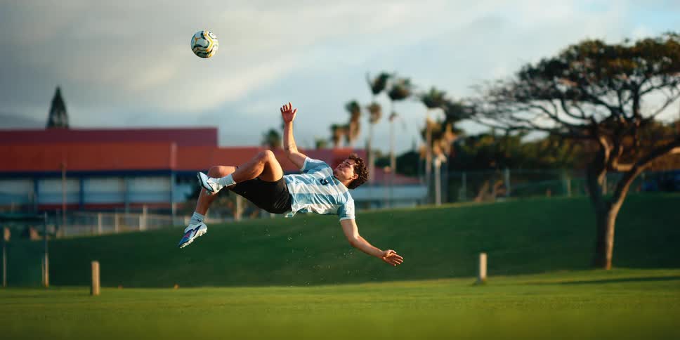 Player performing a bicycle kick to strike a soccer ball on a grass field